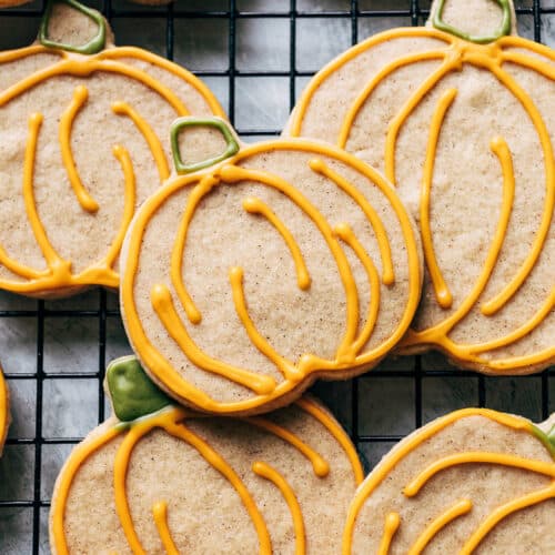 Pumpkin-shaped and iced cookies on a wire rack.
