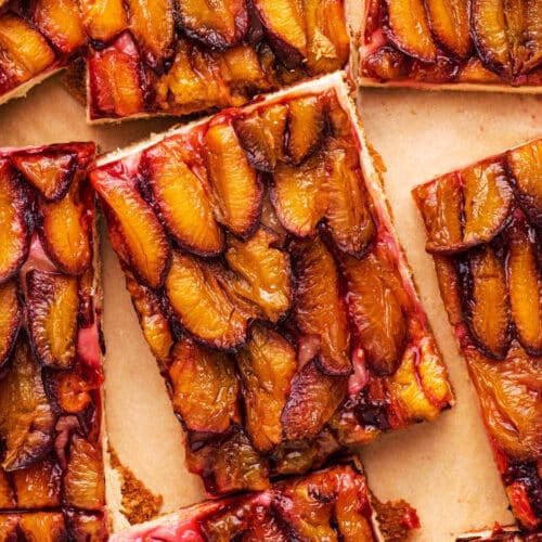 Rectangles of plum cake on parchment paper, top-down view.