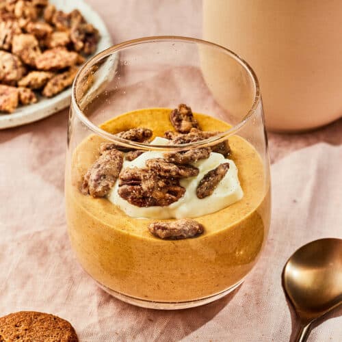 Two glasses filled with pumpkin mousse and topped with cookie crumbles.