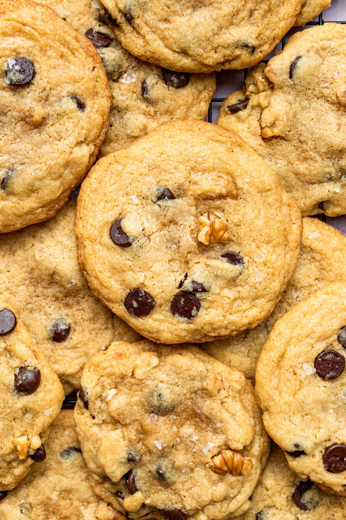 Close up of several walnut chocolate chip cookies piled on top of one another.