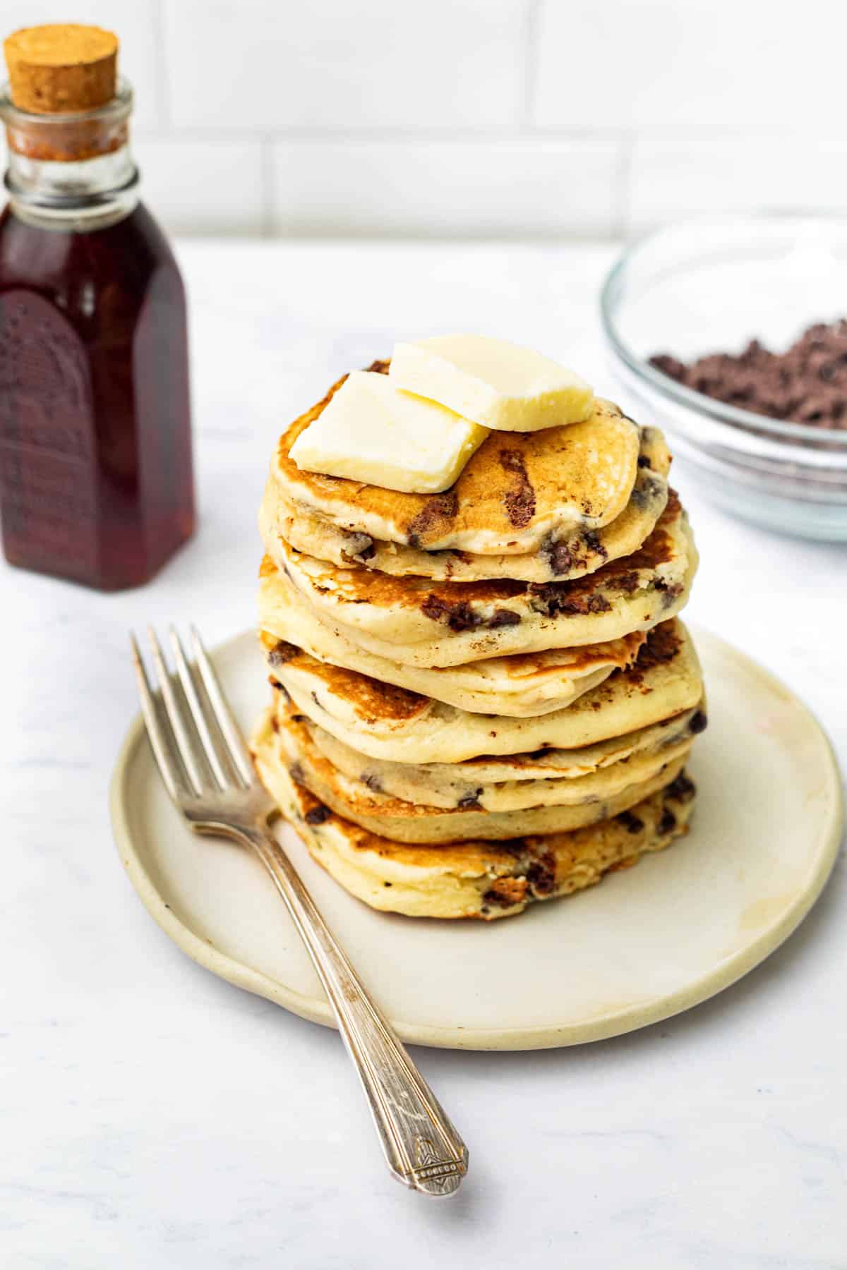 A stack of chocolate chip pancakes with two pats of butter on top.