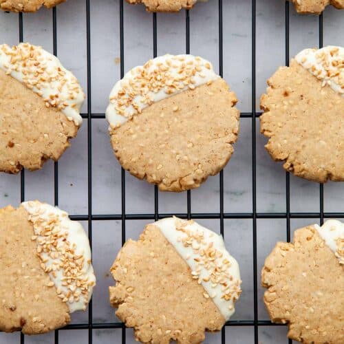 Sesame shortbread dipped in white chocolate on a wire rack.