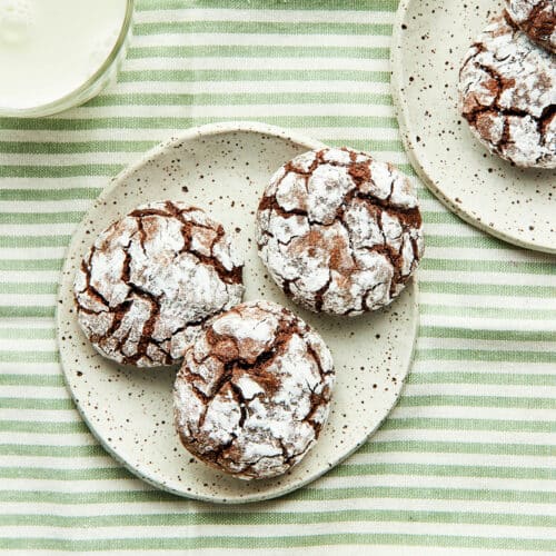 Three small plates with chocolate crinkle cookies on them.