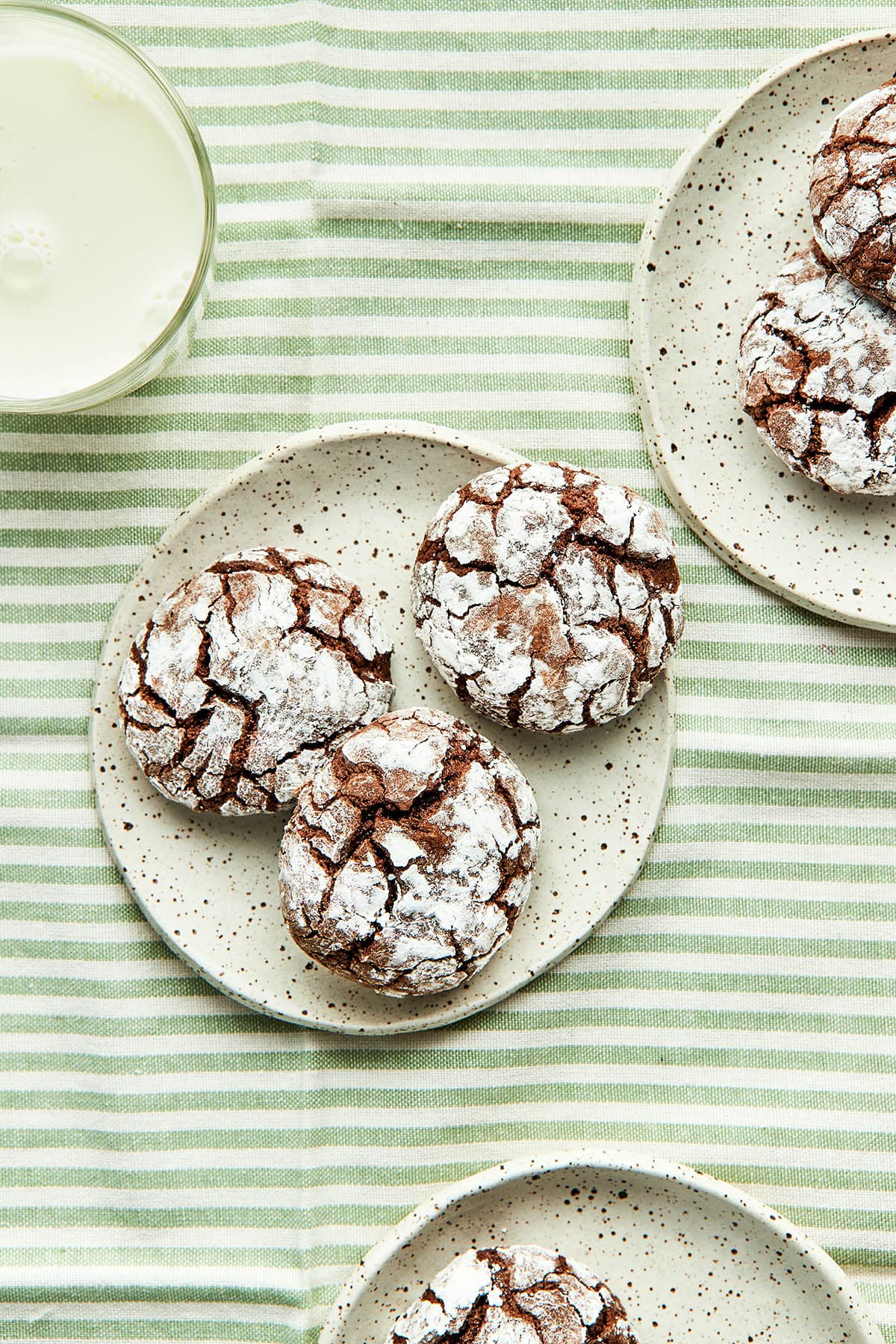 Three small plates with chocolate crinkle cookies on them.