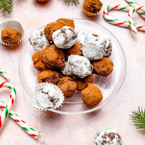 Chocolate truffles rolled in cocoa and sugar, with candy canes around.