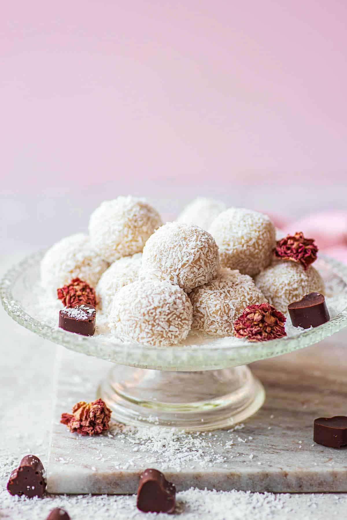 Coconut-coated chocolate truffles on a small glass serving dish.