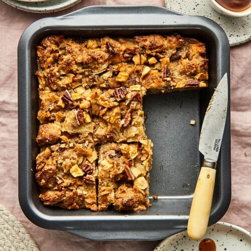 Bread pudding in a square baking tin with two squares removed.