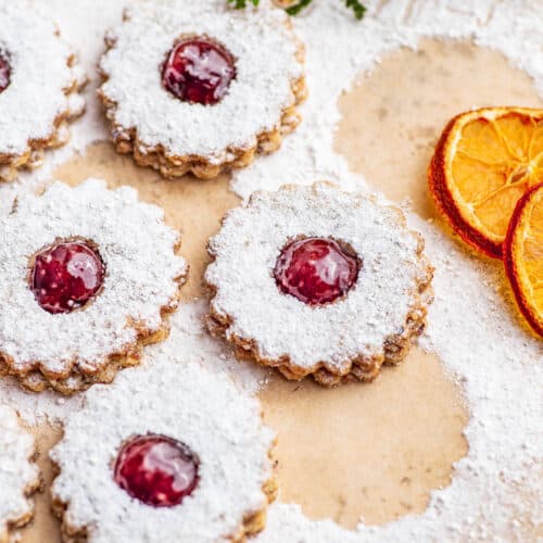 Small icing sugar-topped linzer cookies on parchment paper.