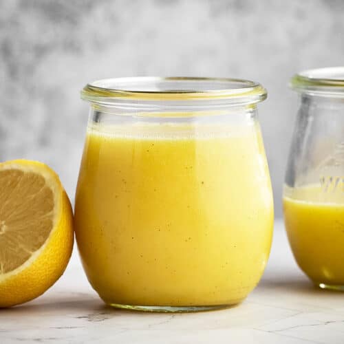 Lemon curd in small jars with a lemon beside.