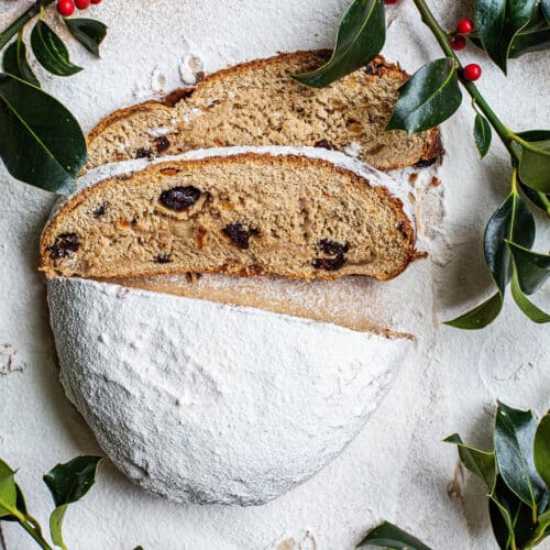 A loaf of icing sugar-covered stollen with two slices cut.