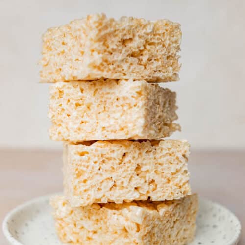 A stack of four rice crisp treats on a small speckled plate.