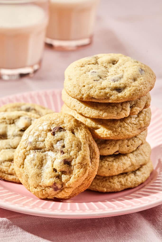 A stack of several chocolate chip cookies with one leaning against the stack.