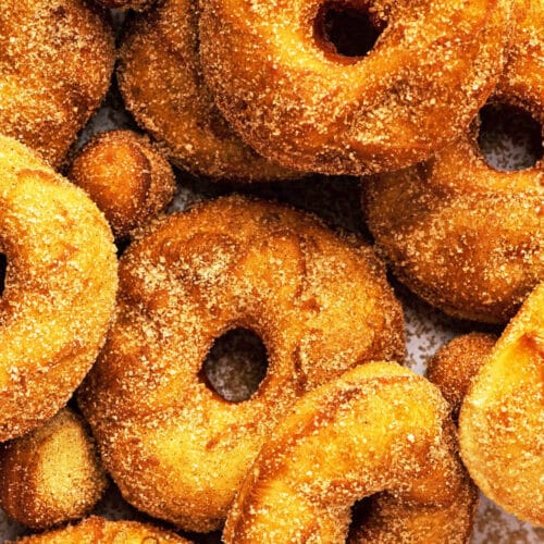 Close up of several cinnamon sugar donuts and donut holes.