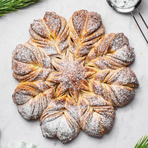 Top-down view of a loaf of star bread or snowflake bread topped with icing sugar.