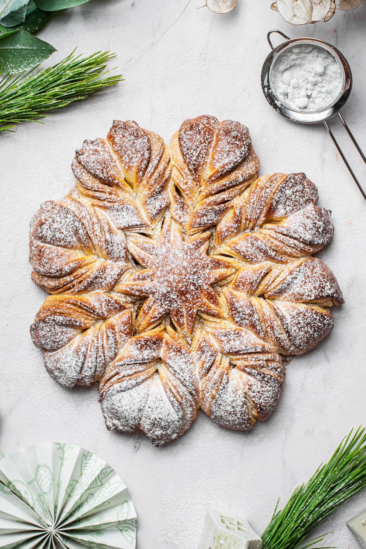 Top-down view of a loaf of star bread or snowflake bread topped with icing sugar.