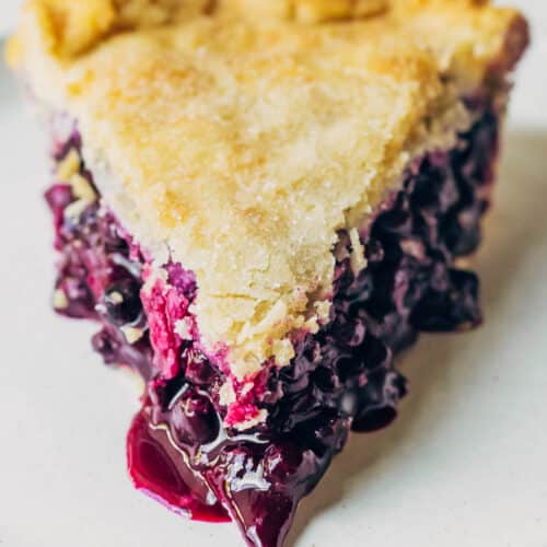 Close up of a slice of blueberry pie on a plate.