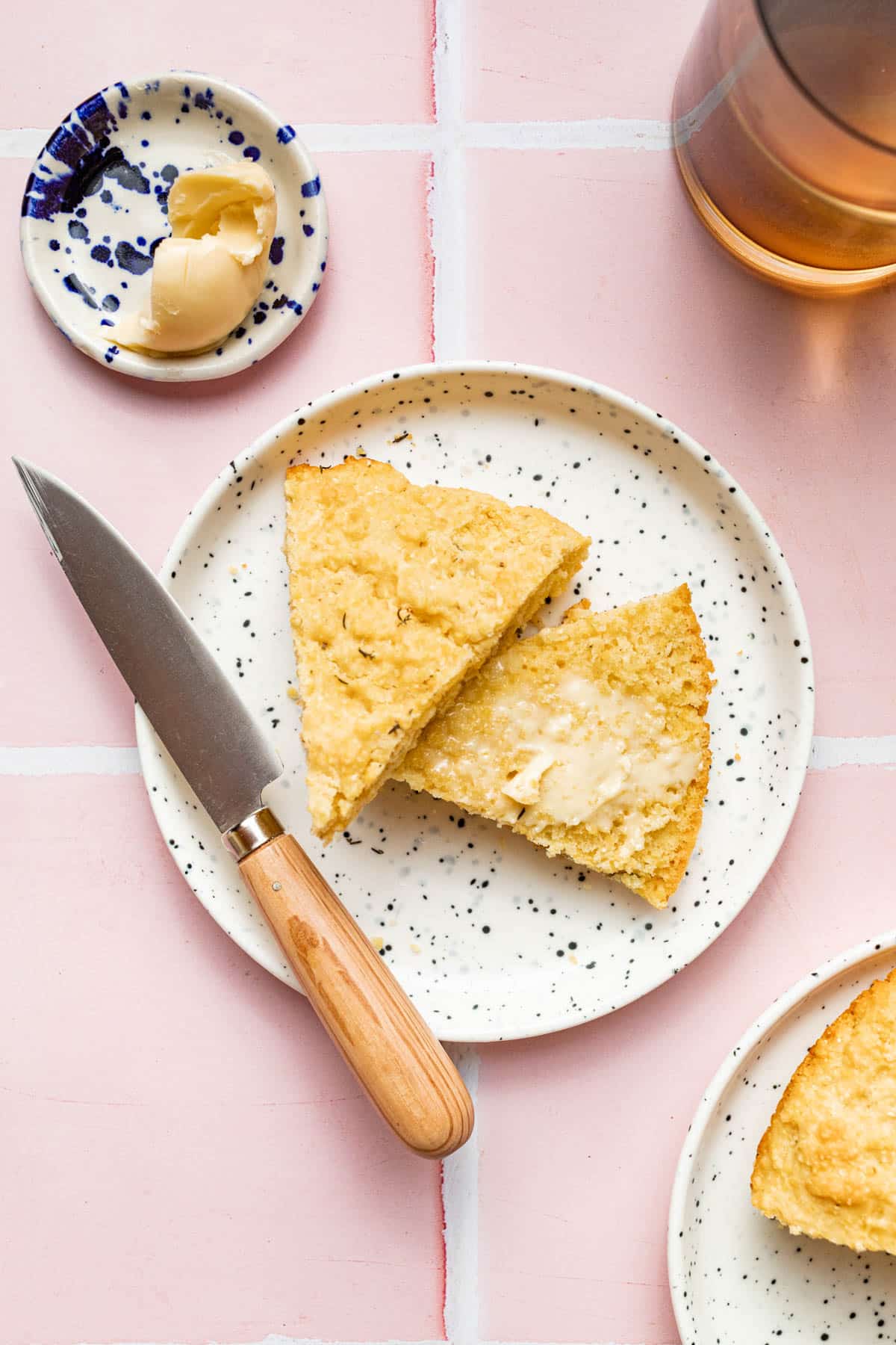 A wedge of cornbread on a plate, halved and with butter.