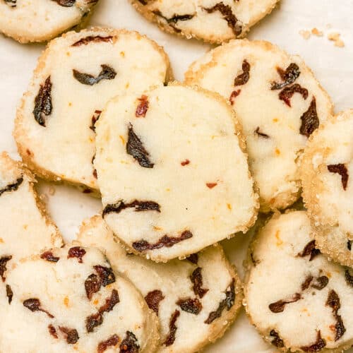 Several cranberry cookies on parchment paper, all piled together.