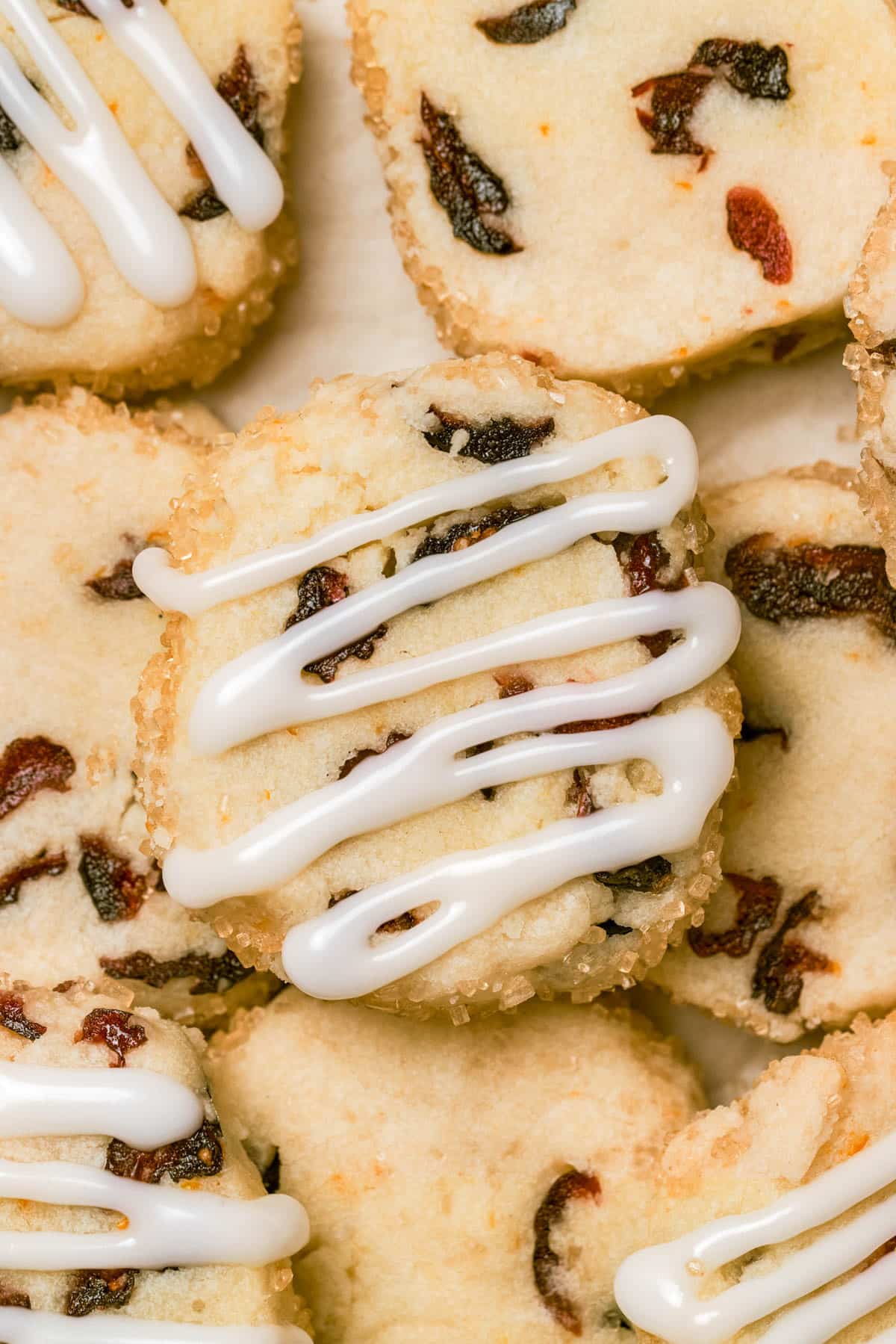 Close up of cranberry cookies, some topped with lines of white icing.