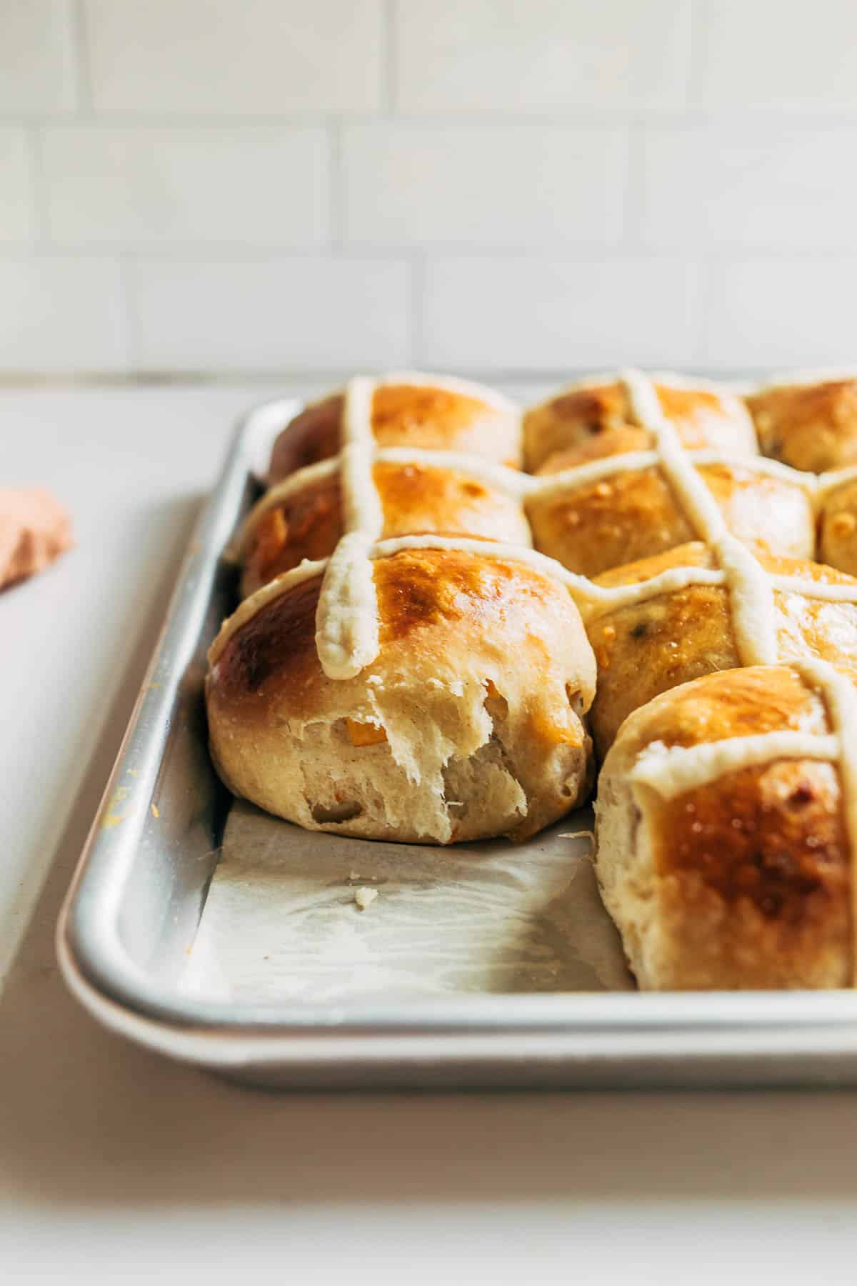 A pan of hot cross buns with one removed.