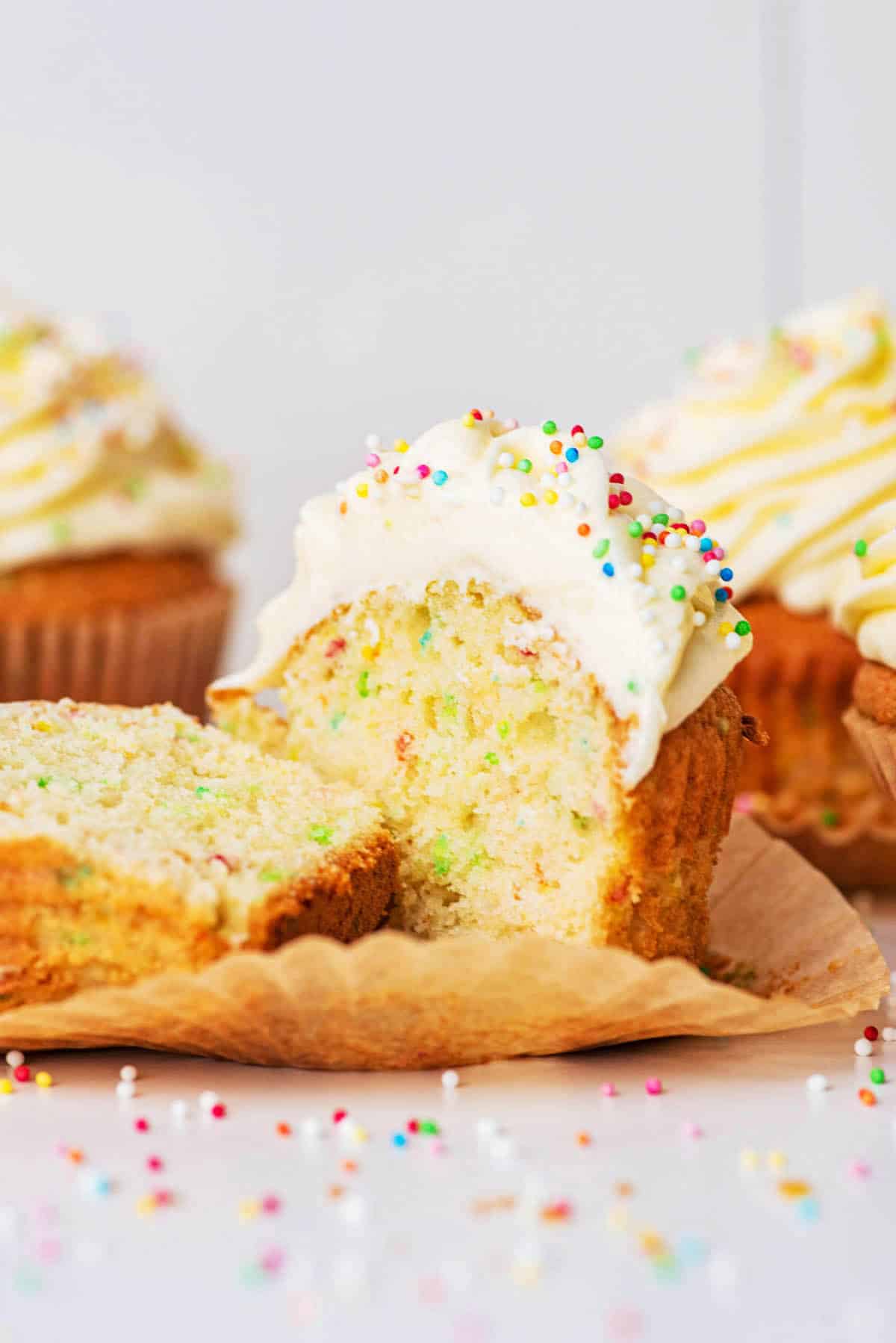 Sprinkle cupcake topped with buttercream, halved to show interior texture and sprinkles.