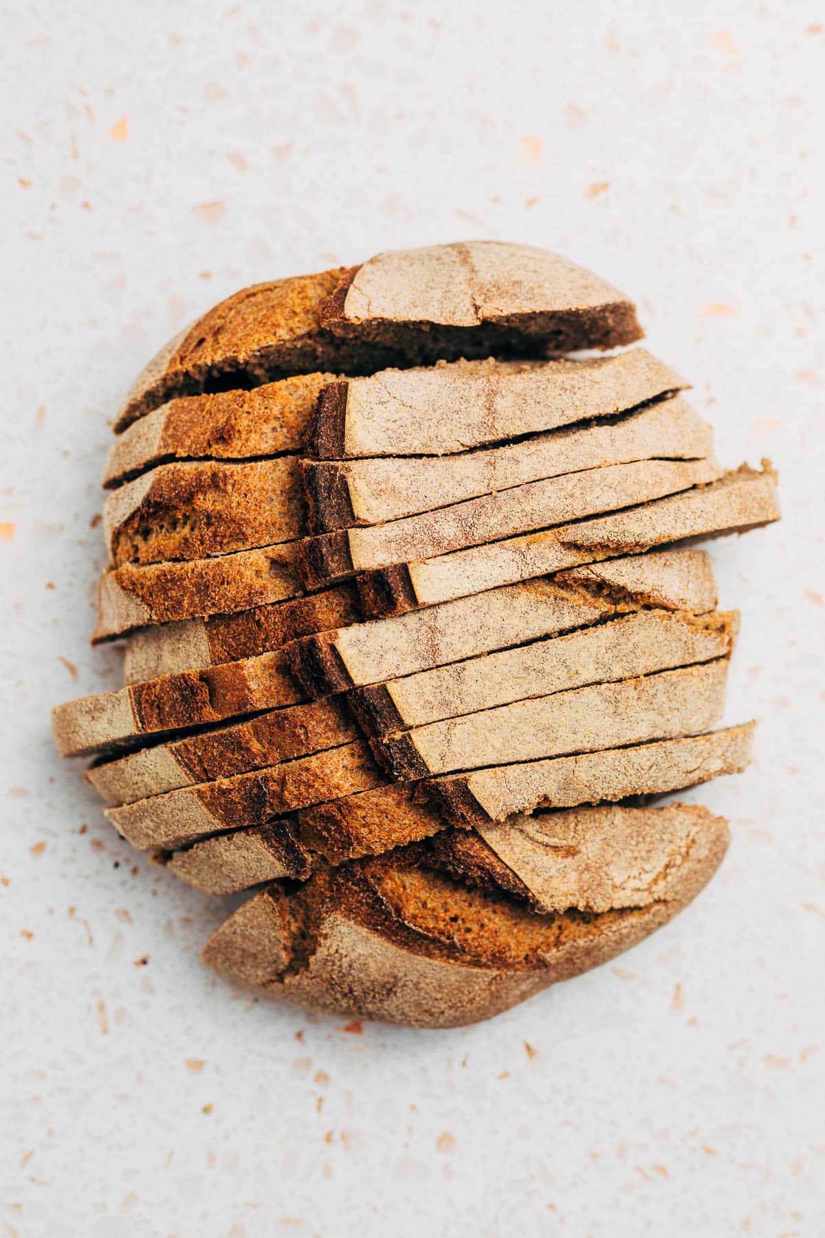 A loaf of whole wheat bread cut into slices, top-down view.
