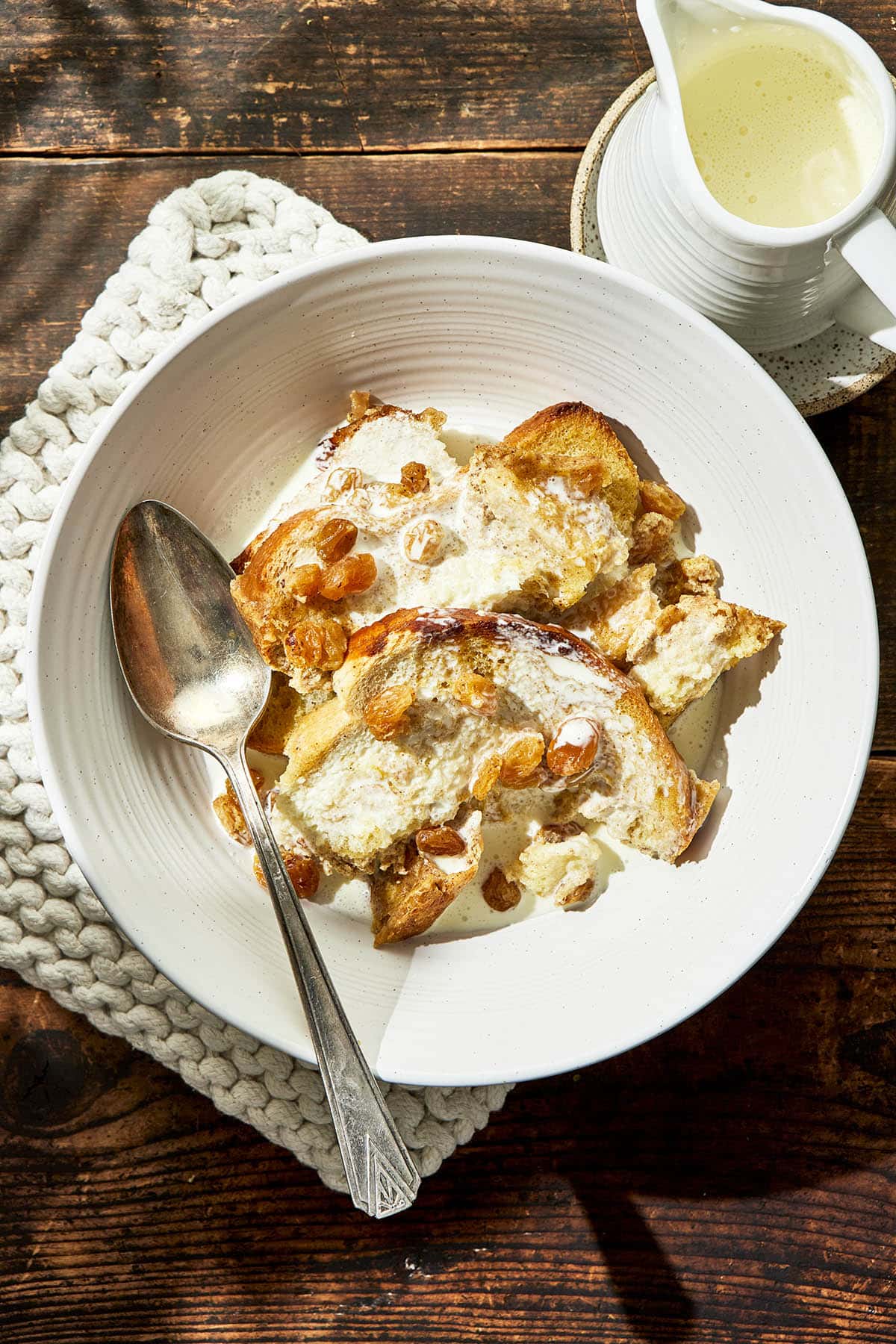 A bowl with bread pudding topped with cream.