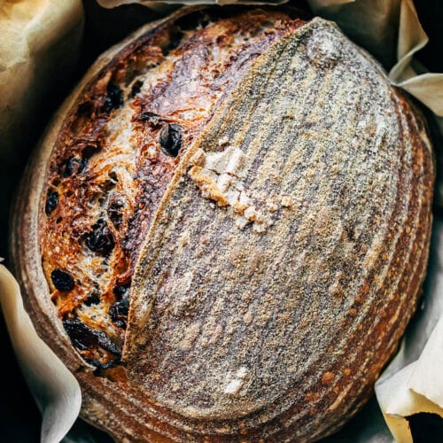 A loaf of raisin sourdough bread in a large pot with parchment paper.