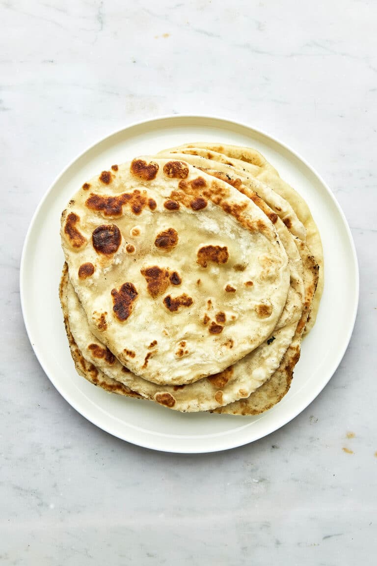 A pile of naan on a plate, top down view.
