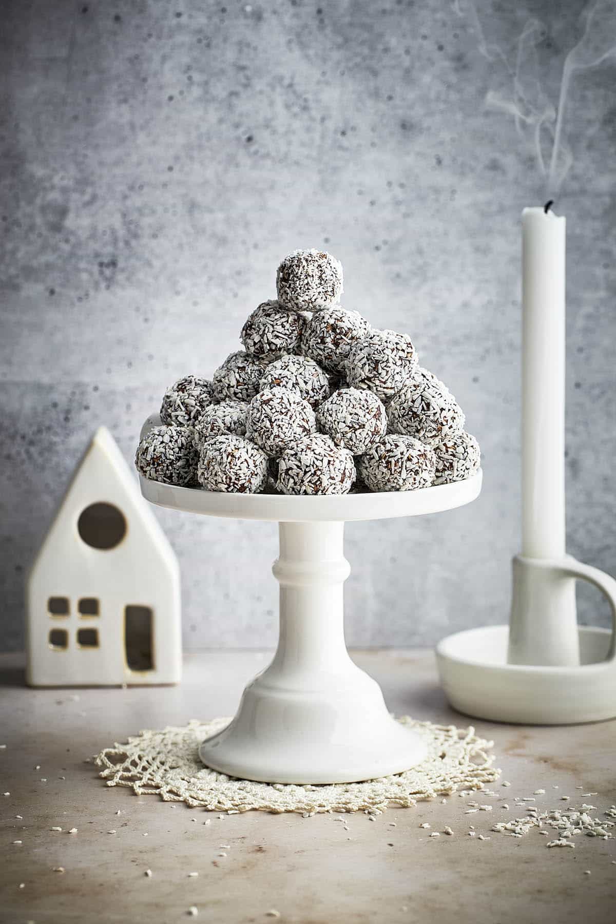 A cake stand piled with chocolate balls with a blown-out candle and ceramic house in background.