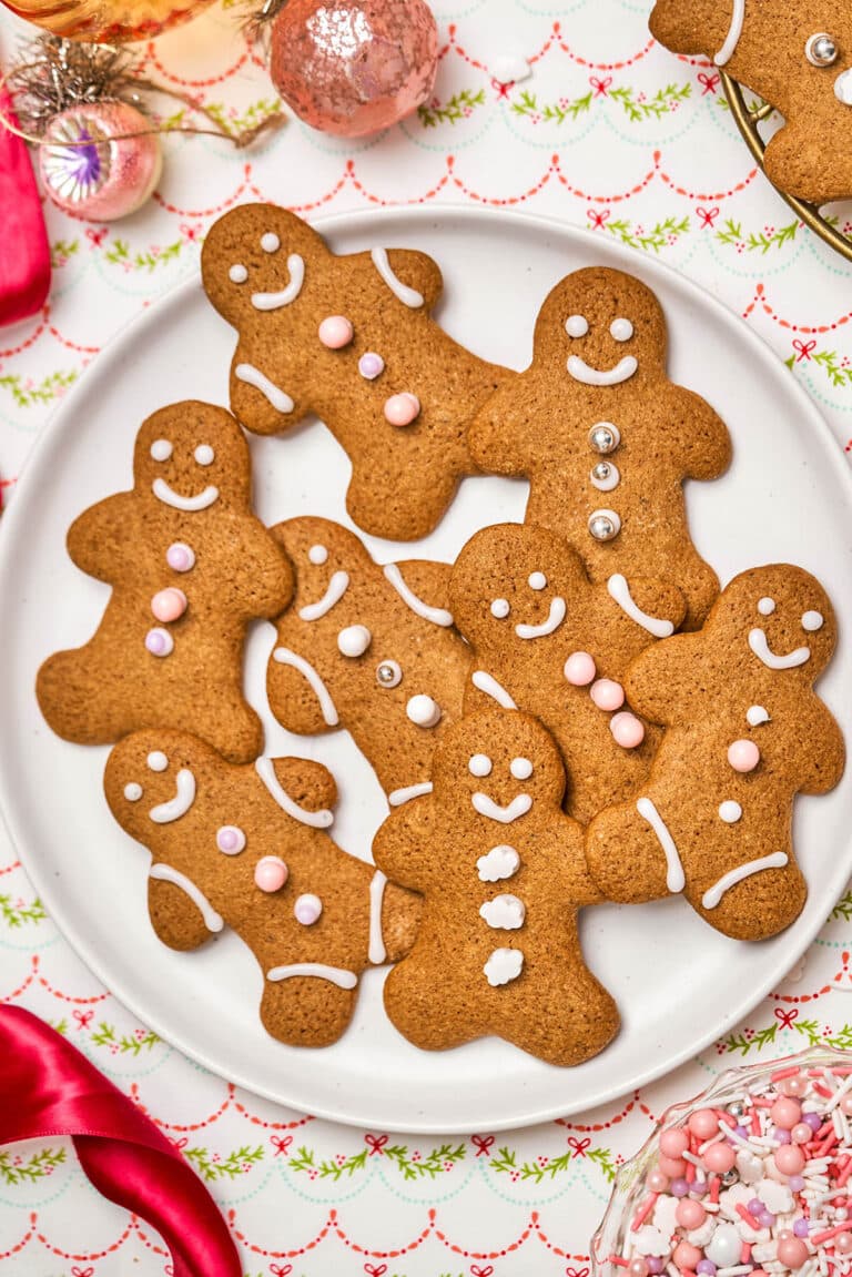 Several gingerbread people, iced and with sprinkles, on a plate.