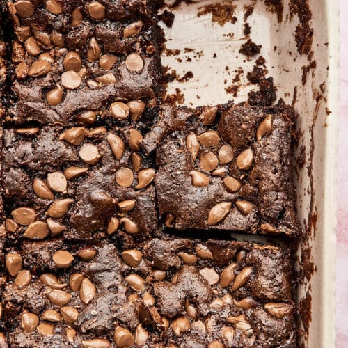 Chocolate cake topped with chocolate chips in a baking dish, cut into squares.