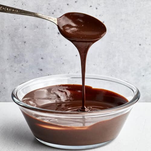 Ganache pouring from a tablespoon over a bowl full.
