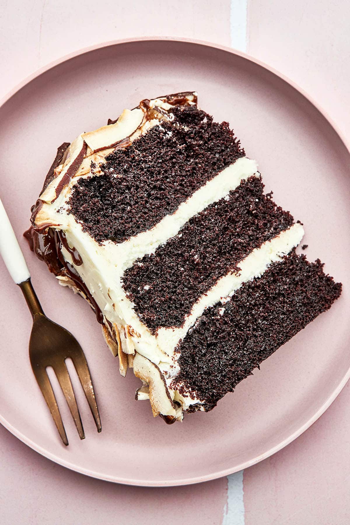 A slice of 3-layer chocolate cake with white frosting and coconut.