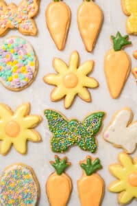 Several pastel-iced cookies in spring shapes like carrots and flowers.