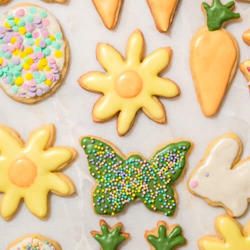 Several pastel-iced cookies in spring shapes like carrots and flowers.