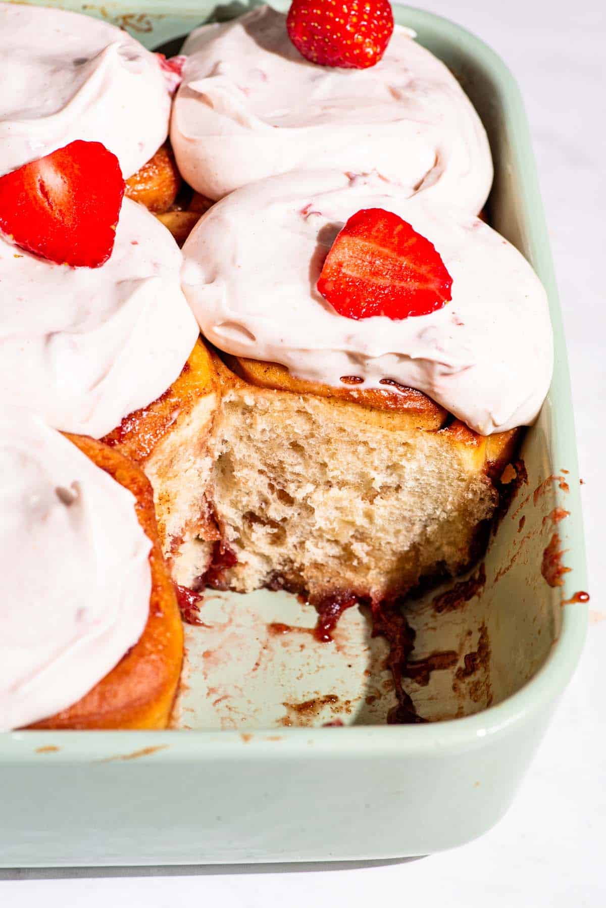 Strawberry rolls with one removed in the baking dish.