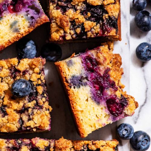 Blueberry cake cut into squares, two squares turned to show cake crumb.