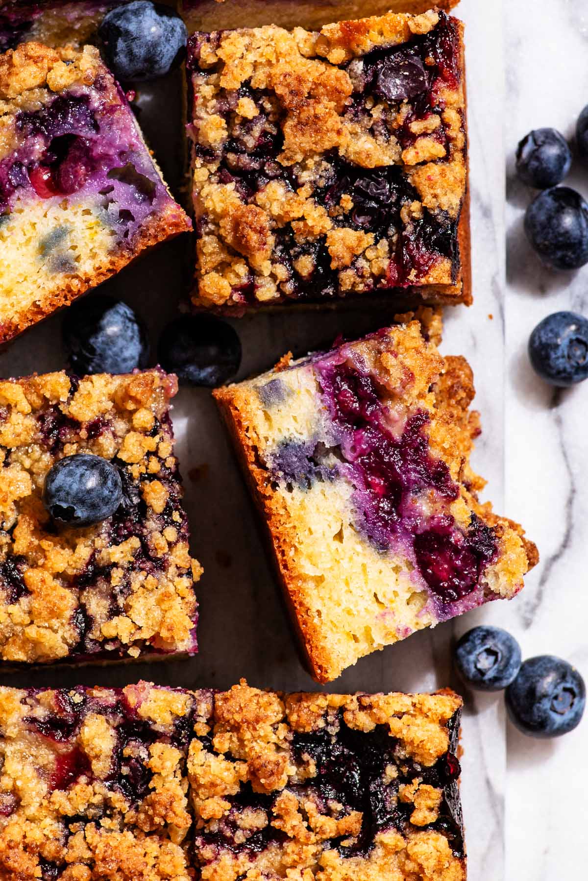 Blueberry cake cut into squares, two squares turned to show cake crumb.