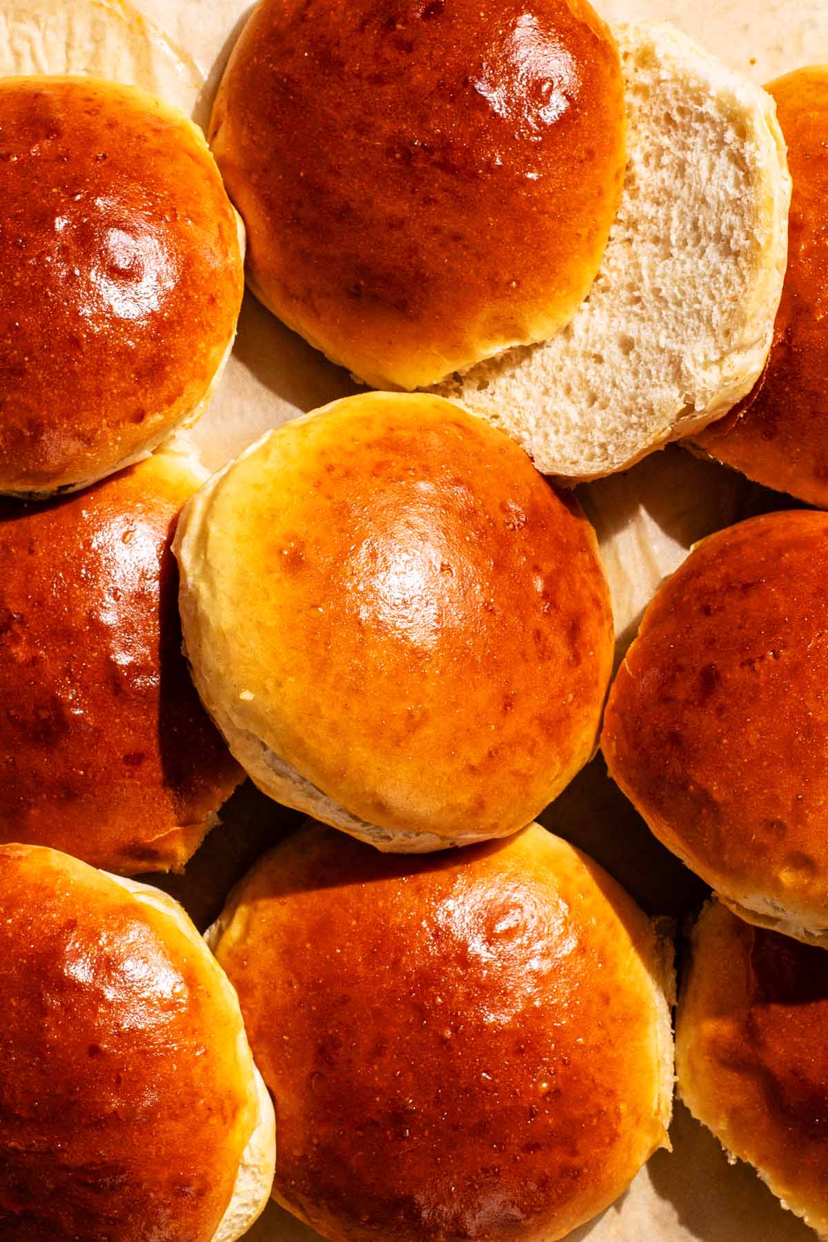 Several shiny burger buns, one sliced.