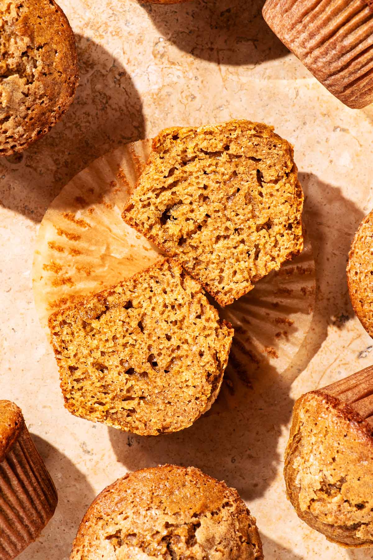 Several whole wheat muffins on a stone worktop, one halved.