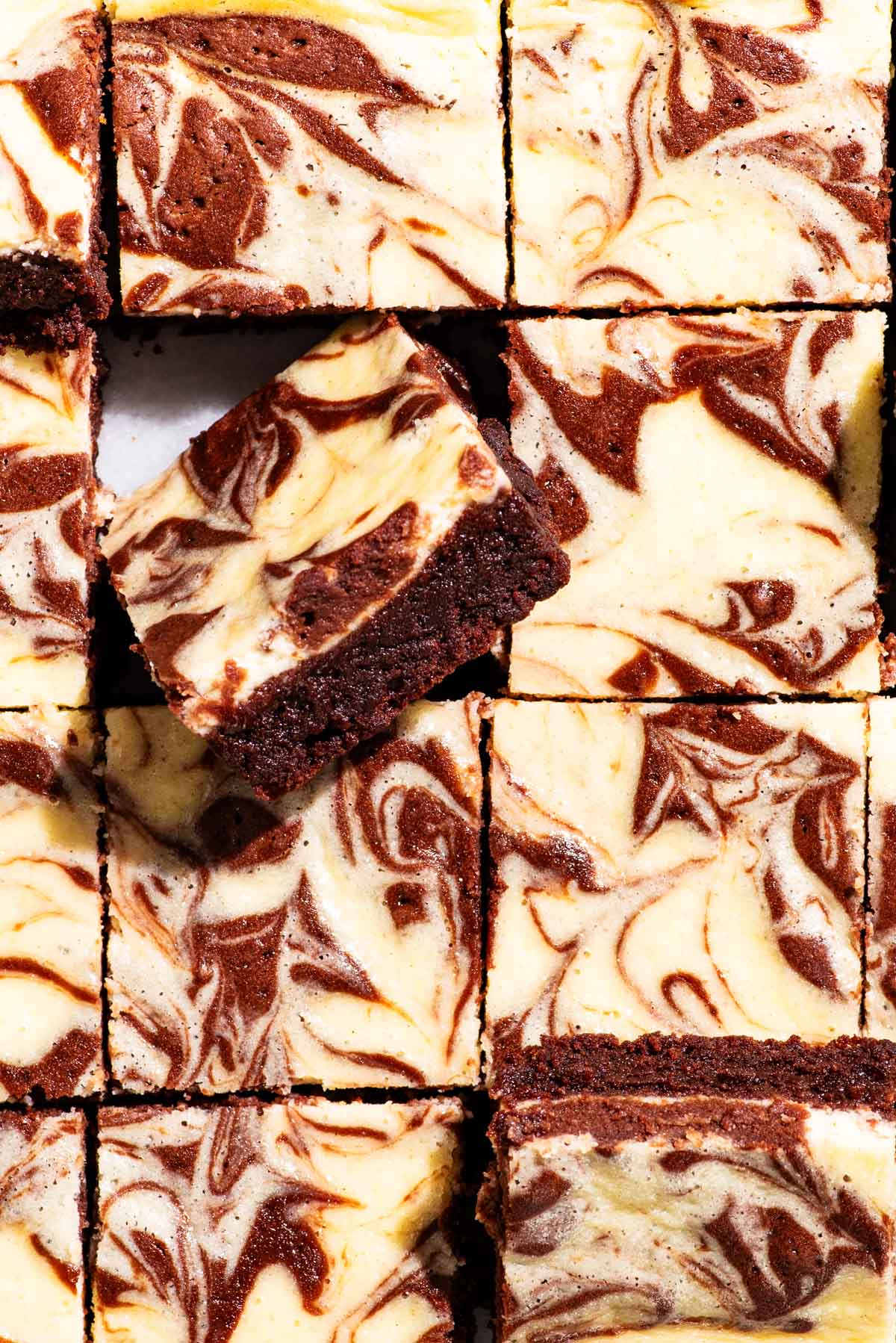 Brownies with a cream cheese swirls, cut into squares with some tipped.
