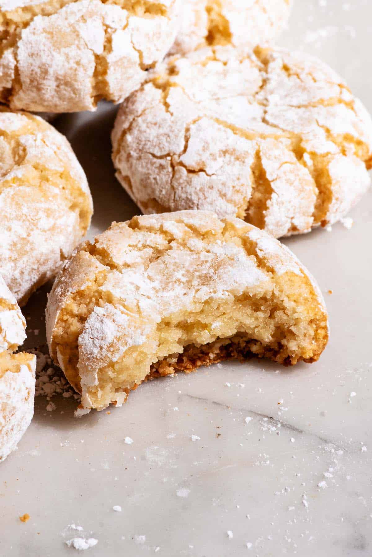 Crinkle cookies on a marble surface, one with a bite taken out of it.