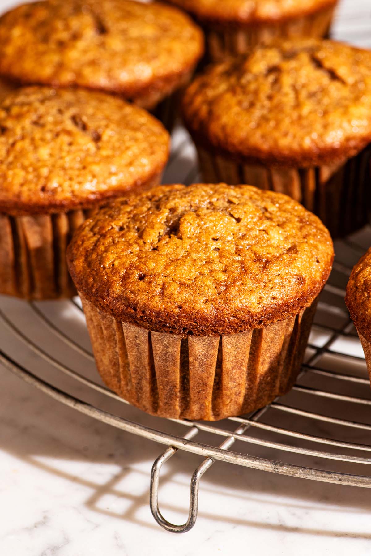 Several muffins on a round wire rack.